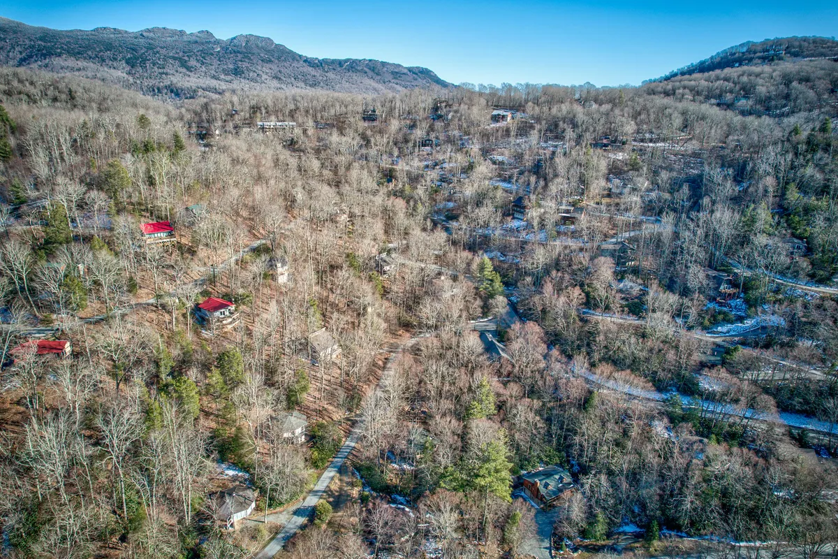 A scenic view of the surrounding area reveals scattered homes among rolling hills and winding roads, all set against a majestic mountain backdrop. The landscape is tranquil, inviting guests to imagine nearby hiking trails, stargazing, and the charm of the High Country environment.