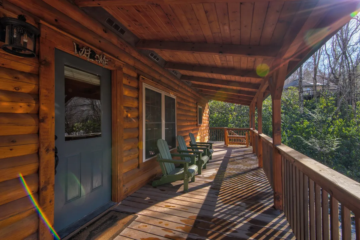This exterior shot features the cabin's rustic log facade with welcoming rocking chairs on the porch, surrounded by greenery. The scene suggests a relaxing spot to unwind after outdoor activities, bridging the transition from adventure to comfort.